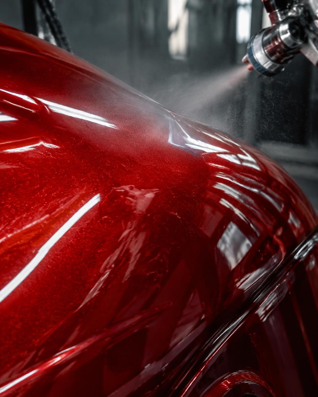 Close-up of fresh metallic red spray paint on a vehicle body